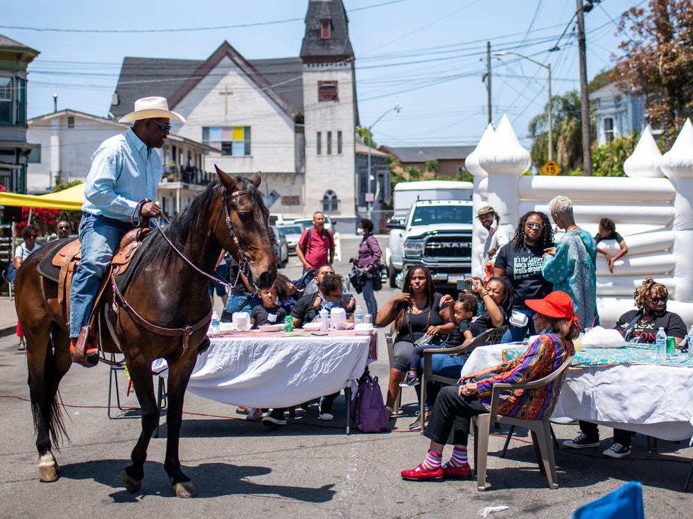 Donnell McAlister and his horse JJ, named after Jesse James, ride through a Juneteenth block party to celebrate the opening of the Black Panther Party Mini Museum in West Oakland on June 19, 2021.