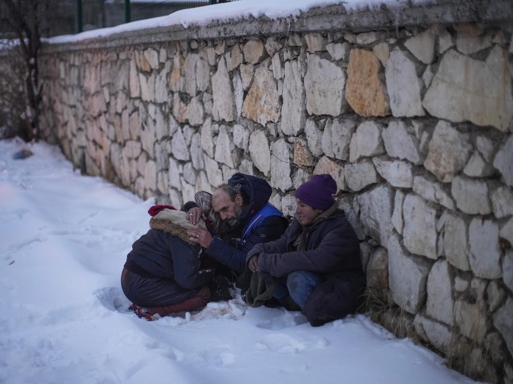 Syrian refugee Ahmad Al-Ahmad, center, husband of Naziha Al-Ahmad, comforts his daughter as they bury Naziha in a cemetery after she died during an earthquake, in Elbistan, southeastern, Turkey, on Feb. 10, 2023. Syrians fleeing their country's civil war were once welcomed in Turkey out of compassion. But as their numbers grew, so did calls for their return.