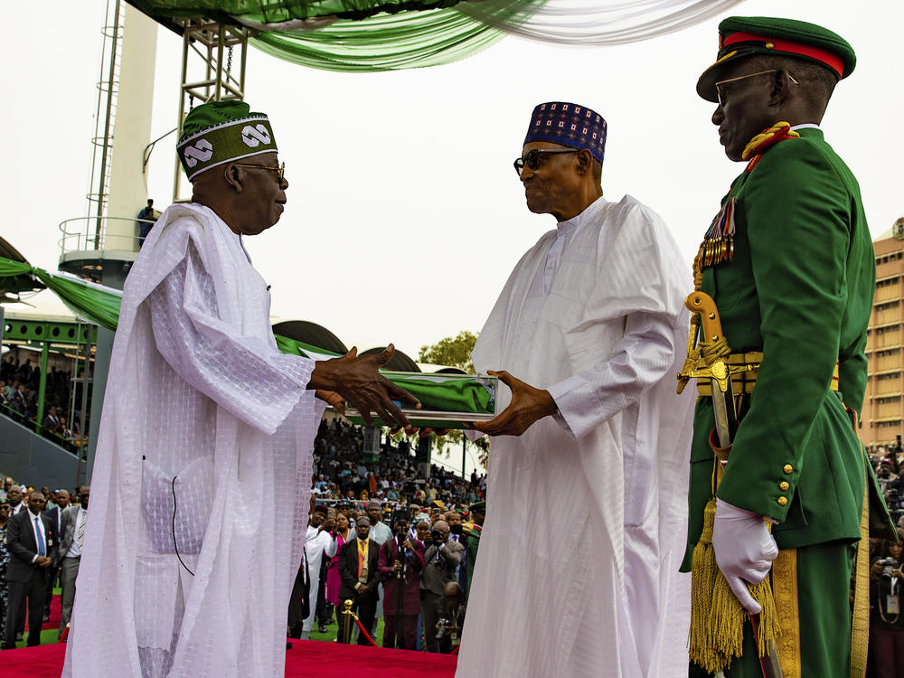 In this photo released by the Nigeria State House, Nigeria's new President Bola Ahmed Tinubu, left, receives Nigeria flags from former Nigerian President Muhammadu Buhari, during the inauguration ceremony in Abuja, Monday, May 29, 2023.