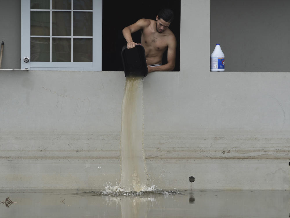 A resident bails water from a flooded home in the aftermath of Hurricane Maria in Catano, Puerto Rico in 2017. Climate change is making hurricanes more dangerous.