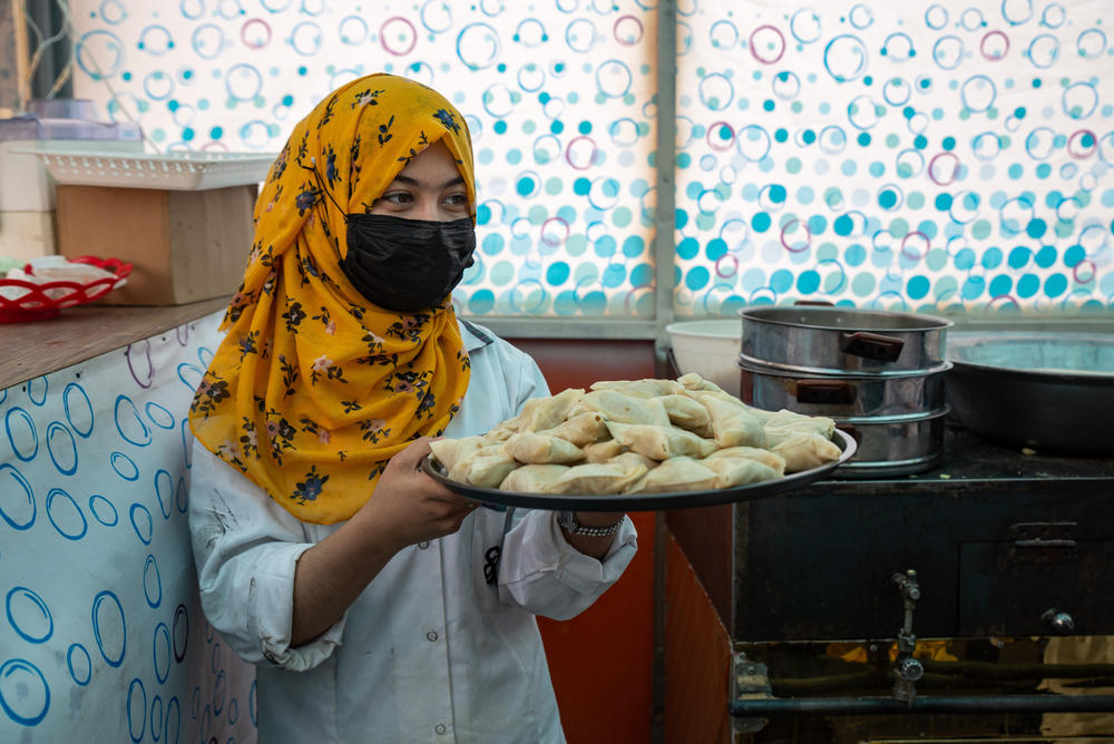 Husna Mohammadi carries a plate of samboose, ready to serve guests at Banowan-e-Afghan restaurant in Kabul.