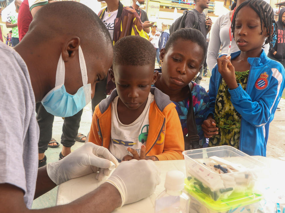 People queue for a free malaria test in Lagos, Nigeria. The country has one of the highest national death tolls from the mosquito-borne disease. A new vaccine offers hope. But logistics could prevent it from reaching the arms of those who are eligible.