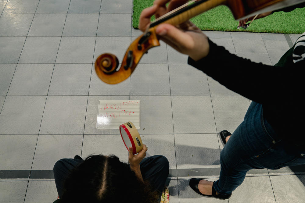 A juvenile detention center resident plays tambourine in collaboration with Sound Impact violinist <a href=