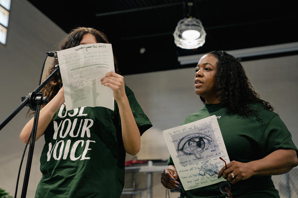 A Northern Virginia Juvenile Detention Center resident reads a poem alongside Sound Impact board member Keisha Johnstone.