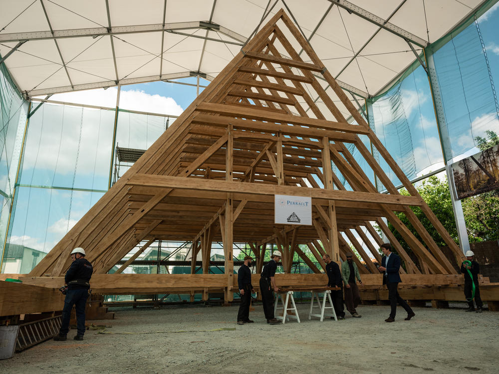 Carpenters at the Ateliers Perrault finalize the practice assembly of the <em>charpente</em>, or roof framework of the choir — the part of the cathedral that provides seating for the clergy and choir — on May 25. It extends nearly 50 feet long by 33 feet high.