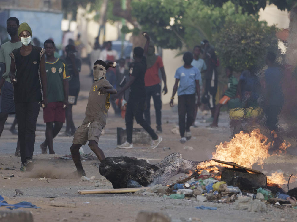 A demonstrator throws a rock at police during a protest at a neighborhood in Dakar, Senegal, on Saturday. The clashes first broke out after opposition leader Ousmane Sonko was convicted of corrupting youth and sentenced to two years in prison.