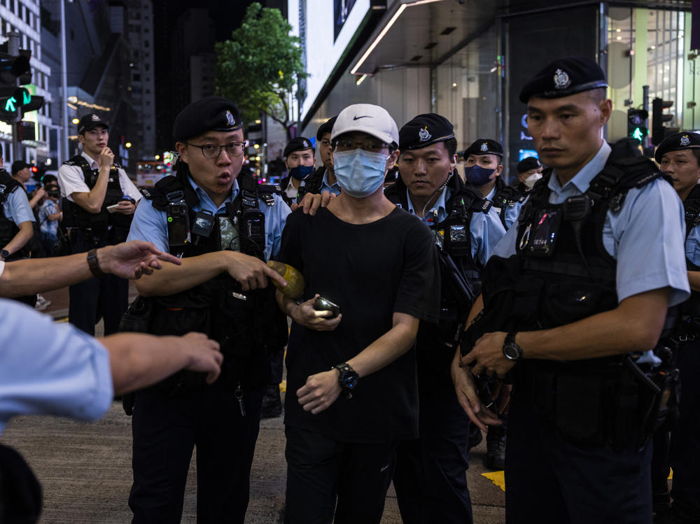 A member of the public is escorted by police after shining the light from a smartphone, near Victoria Park, the city's venue for the annual 1989 Tiananmen massacre vigil, on the 34th anniversary of China's Tiananmen Square crackdown in Hong Kong on Sunday.