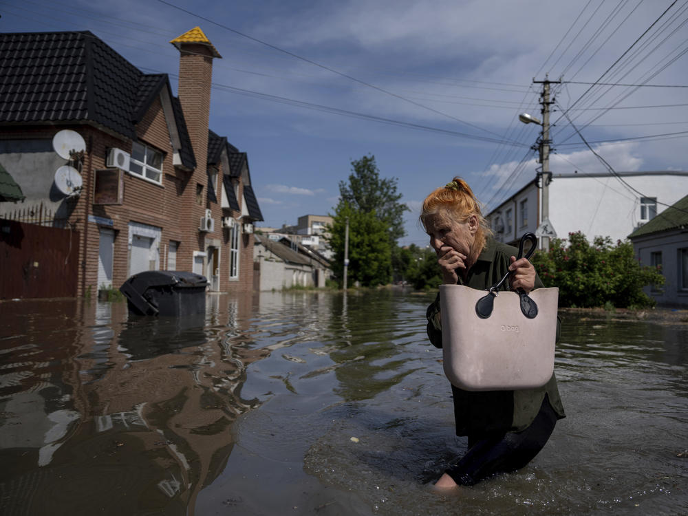 A local resident makes her way through a flooded road after the walls of the Kakhovka dam collapsed overnight, in Kherson, Ukraine.
