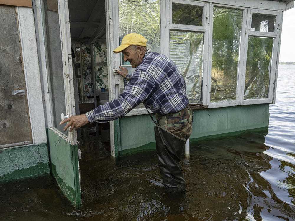 In this photo from May 18, Mykola Gurzhiy, 74, a fisherman, opens a door to his flooded house on an island in the Kakhovka Reservoir on Dnipro River. The dam that creates the reservoir collapsed on Tuesday, with both Ukraine and Russia blaming each other.