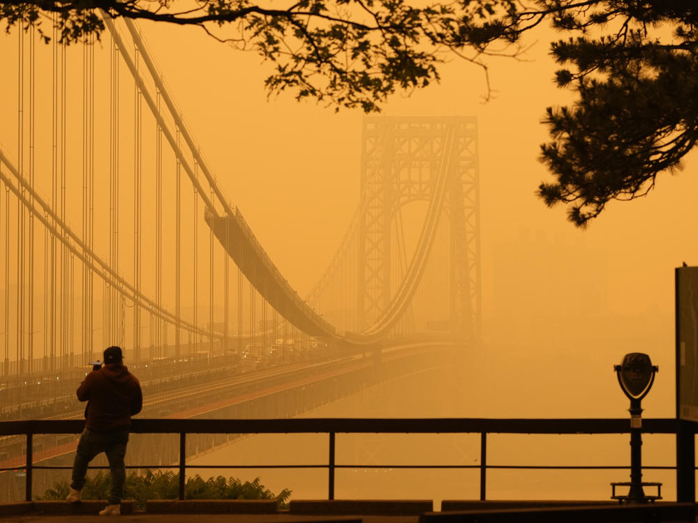 A man talks on his phone as he looks through the haze at the George Washington Bridge from Fort Lee, N.J., on Wednesday.