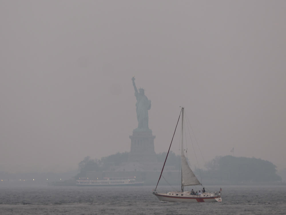 The Statue of Liberty stands shrouded in a reddish haze as a result of Canadian wildfires on Tuesday.