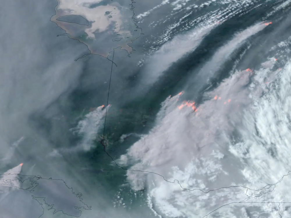 In this GOES-16 GeoColor and fire temperature satellite image taken Tuesday, June 6, 2023 at 6:40 p.m. EDT and provided by CIRA/NOAA, smoke from wildfires burning in the Canadian Provinces of Quebec, right, and Ontario, left, drift southward.