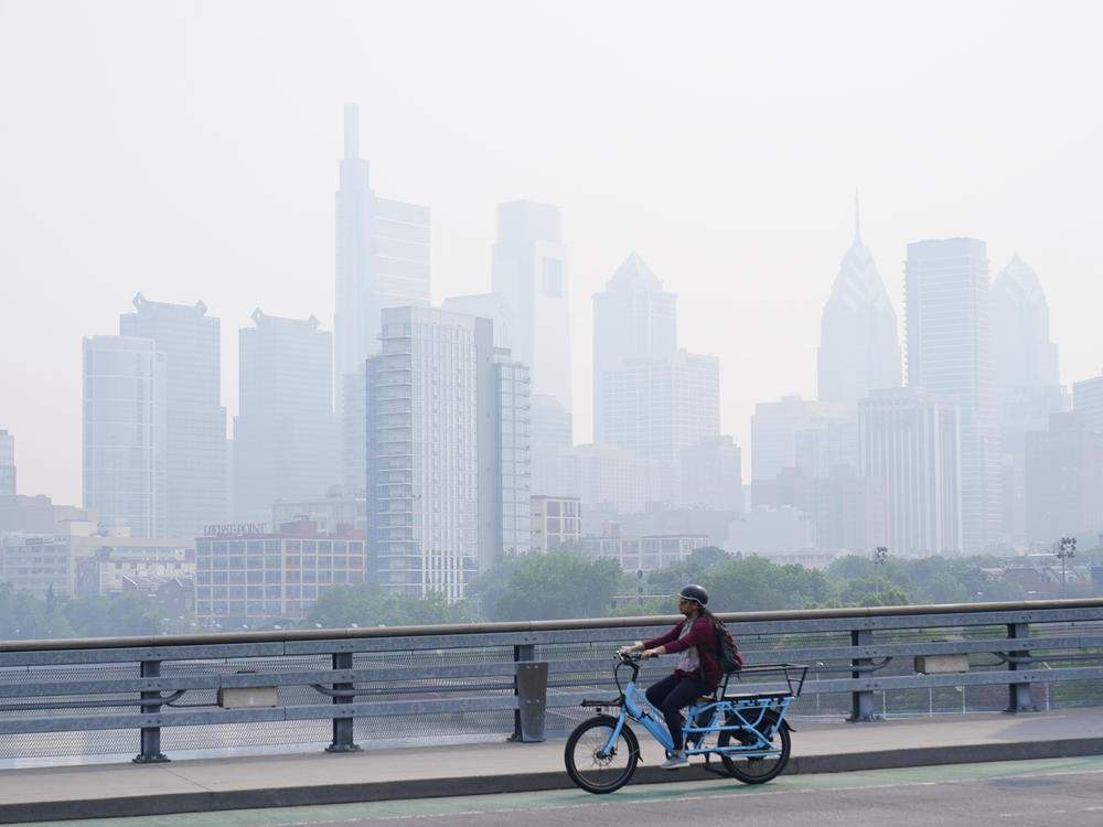 A person cycles past the skyline in Philadelphia shrouded in haze on Thursday.