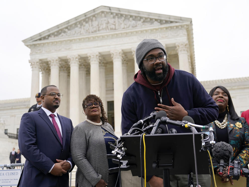 Evan Milligan, center, plaintiff in an Alabama redistricting case, speaks following Supreme Court oral arguments on Oct. 4, 2022. The court on Thursday ruled in favor of Milligan in the case, ordering the creation of a second Alabama congressional district with a large Black population.