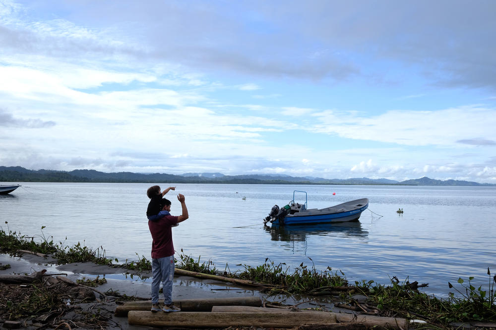 Migrants look out at the bay toward the hills of the Darien from the town of Necoclí.