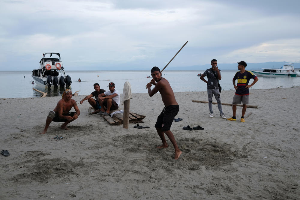 Migrants play a ball game on the beach.