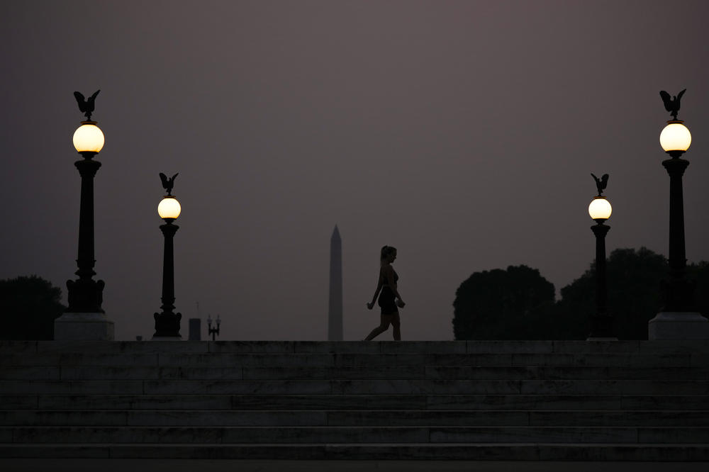 A person walks by the Washington Monument at dusk through hazy skies caused by Canadian wildfires on June 7, 2023 in Washington, D.C.