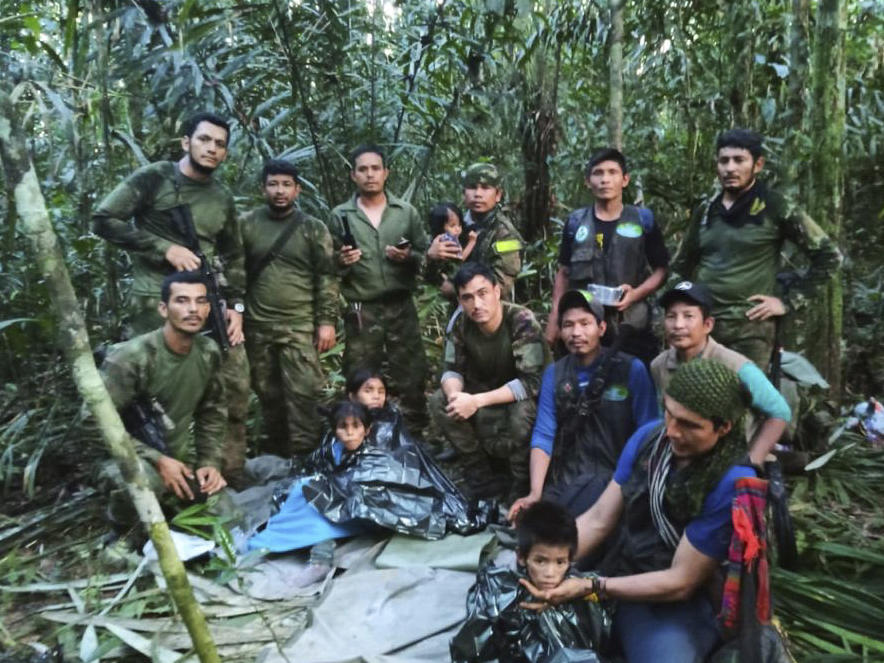 In this photo released by Colombia's Armed Forces Press Office, soldiers and others pose for a photo on Friday with the four children who were missing after a deadly plane crash in the Solano jungle, Caqueta state, Colombia.