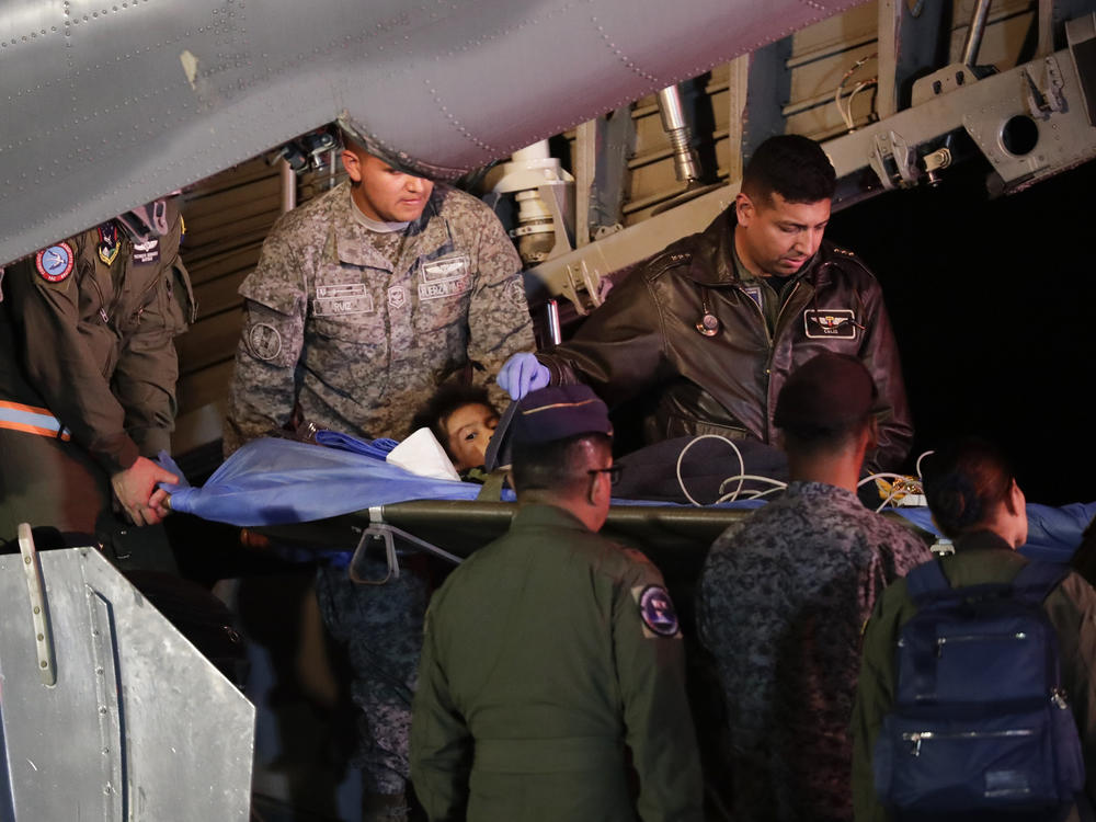 On Saturday in Bogota, Colombia, military personnel unload from a plane one of four Indigenous children who were missing after a deadly plane crash.
