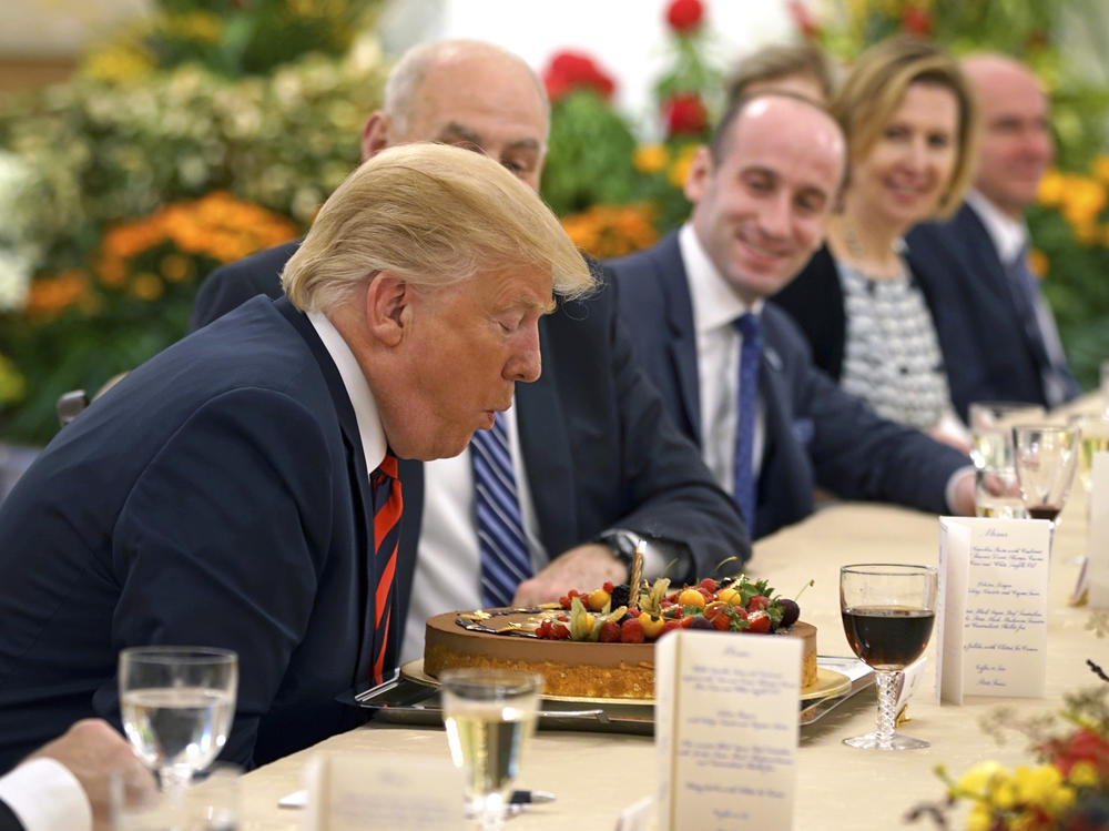 Then-President Donald Trump blows out a candle on a cake celebrating an early birthday during lunch with Singapore's Prime Minister Lee Hsien Loong on June 11, 2018.