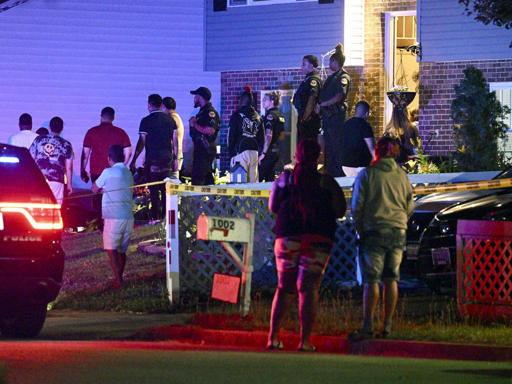 Police stand among a crowd outside a home where multiple people were shot in Annapolis, Md., on Sunday, June 11, 2023.