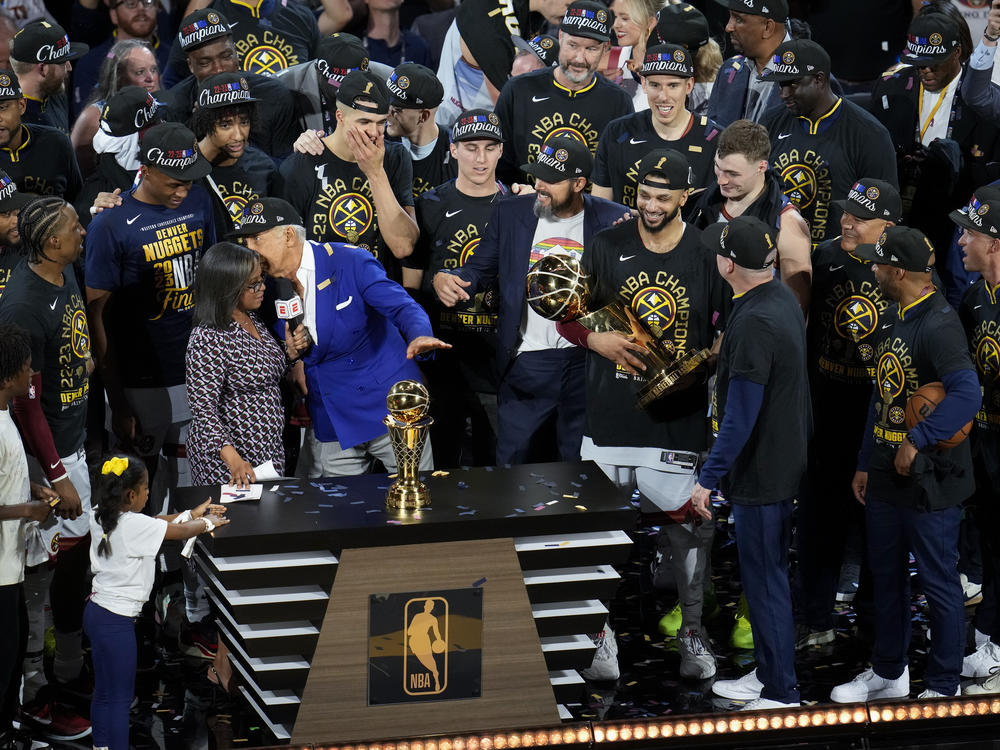 Denver Nuggets players, coaches and owners hold up the Larry O'Brien NBA Championship Trophy after the team's victory over the Miami Heat in Game 5 of basketball's NBA Finals, Monday, June 12, 2023, in Denver.