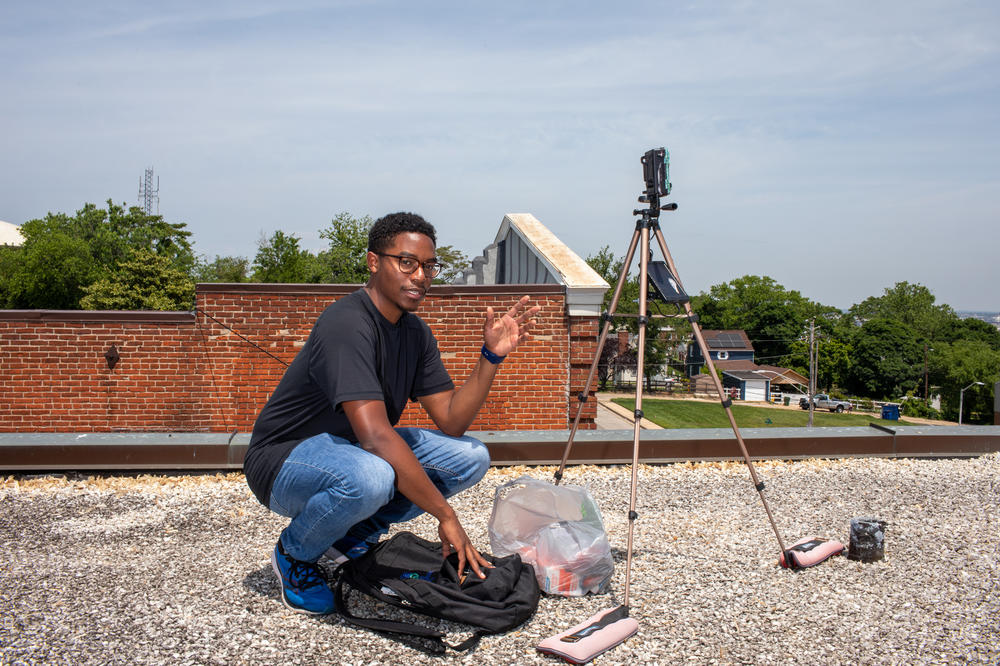Researcher Matthew Aubourg checks an air monitor he installed on the roof of a car detailing shop in the Curtis Bay neighborhood of Baltimore, Md. The shop is right next to a railroad facility where trains unload carloads of coal, releasing dust into the air.