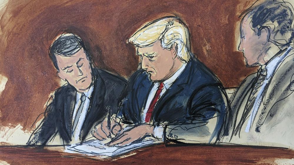 Former President Donald Trump (center) flanked by his defense attorneys, signs his bond in federal court in Miami.