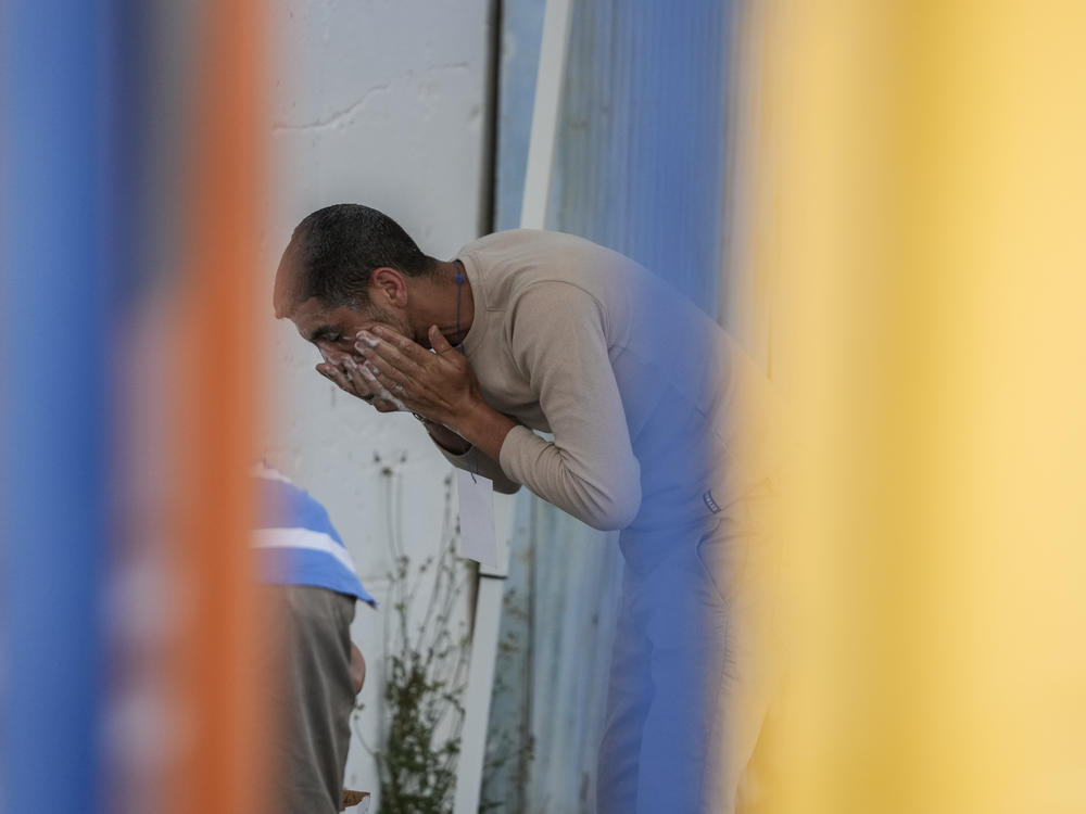 A survivors of a shipwreck washes his face outside a warehouse at the port in Kalamata town, about 240 kilometers (150miles) southwest of Athens on Wednesday, June 14, 2023.