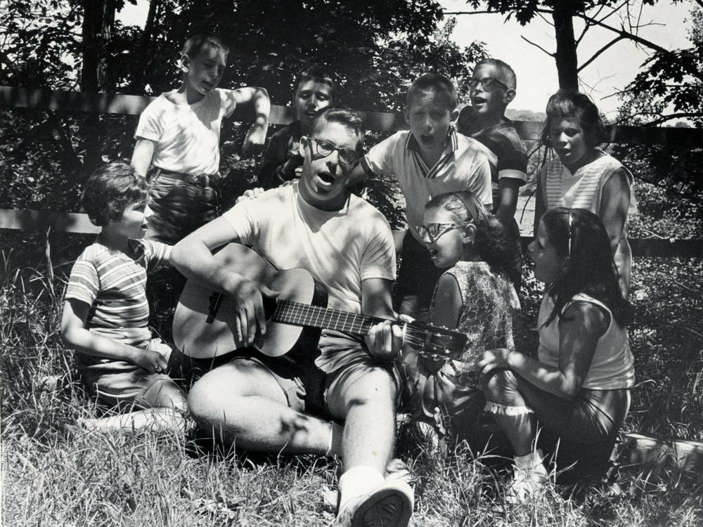 A camp counselor plays the guitar and leads children in singing at Camp Butwin in Minnesota in 1962.