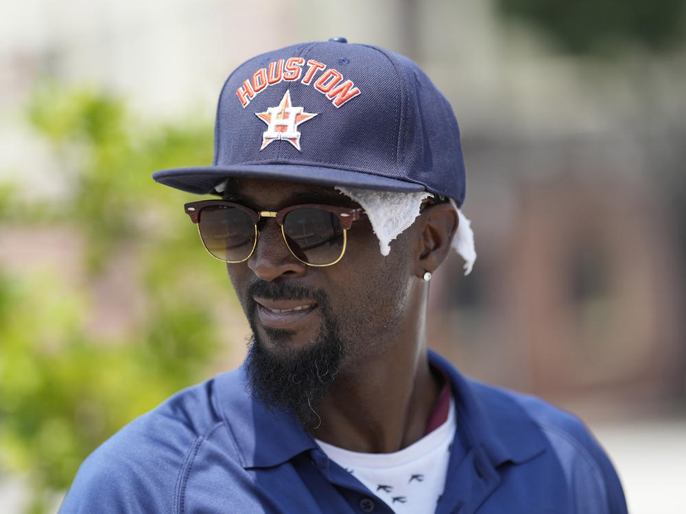 Parking lot attendant Donnay Wright wears a towel under his ball cap as he tries to keep cool in the heat outside Minute Maid Park before a baseball game between the Cincinnati Reds and Houston Astros Saturday, June 17, 2023, in Houston.