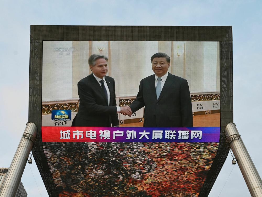 A China Central Television news broadcast shows footage of US Secretary of State Antony Blinken (L) meeting with China's President Xi Jinping, on a giant screen outside a shopping mall in Beijing on June 19, 2023.