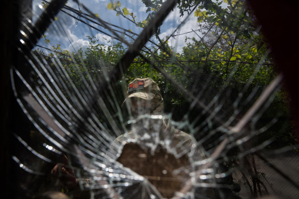 Alex stands behind a crack in the glass on the door of his home.