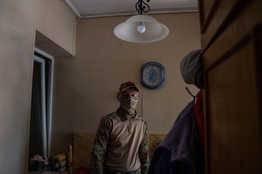 Alex stands just inside his doorway as shelling can be heard at regular intervals outside.