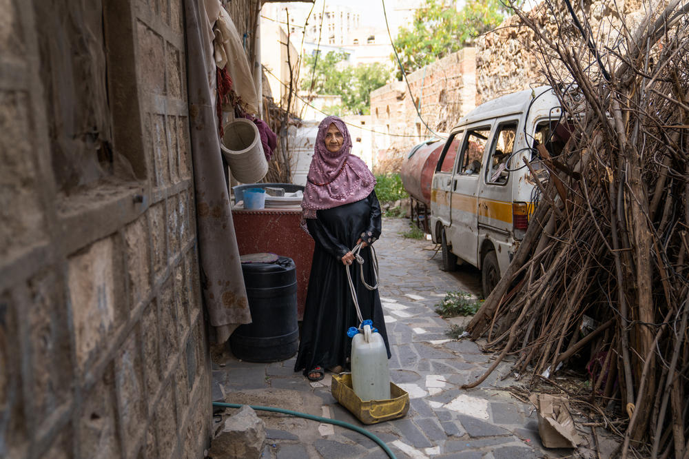 Nimah Said Ahmed Numan, Numan's sister, drags a jug of water to her home in a makeshift sled in Al Dawah. People have to collect water from tanks set out by aid organizations or paid for by private donors, the city doesn't provide water to front-line neighborhoods.