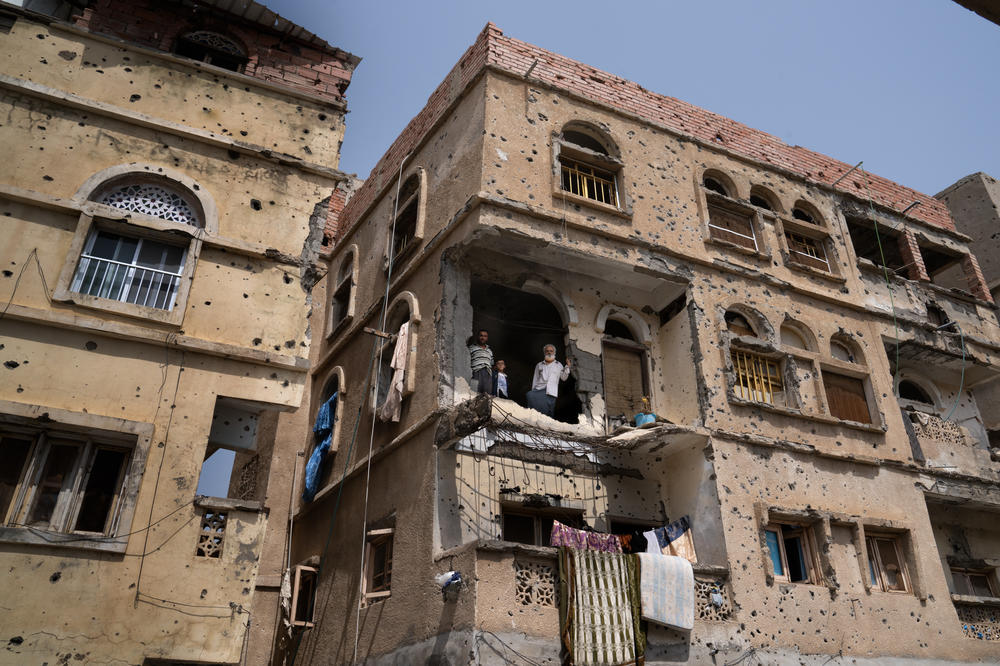Numan (right), stands looking out of the hole in his building where it was struck by a rocket.