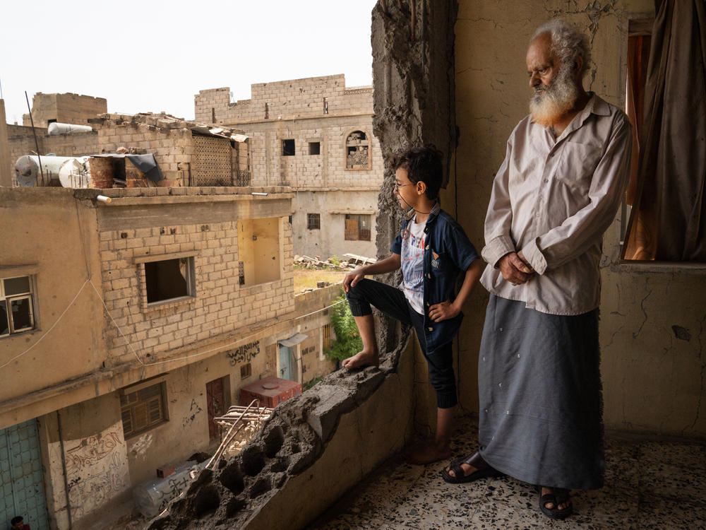 Abdullah Saif Ahmed Numan and his grandson, Mohammad, stand in the building where they live in Al Dawah neighborhood of Taiz, Yemen. The neighborhood is on the front line of a divided city in Yemen's civil war.