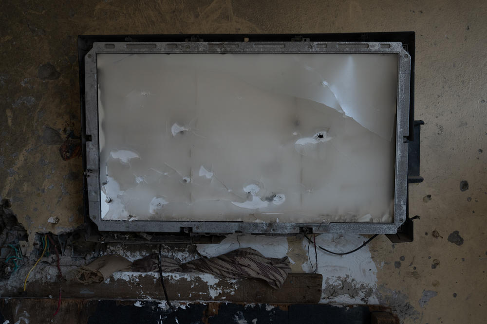 A tv remains mounted on the wall in Numan's home, with bullet holes and cracks.