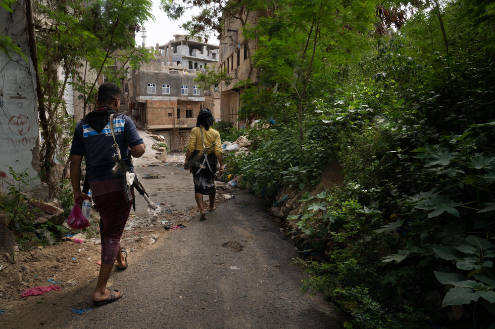 Two members of the military in Taiz walk down a road that is often targeted by snipers from the Houthi side of the city. A thin curtain currently protects the road from the view of the snipers.