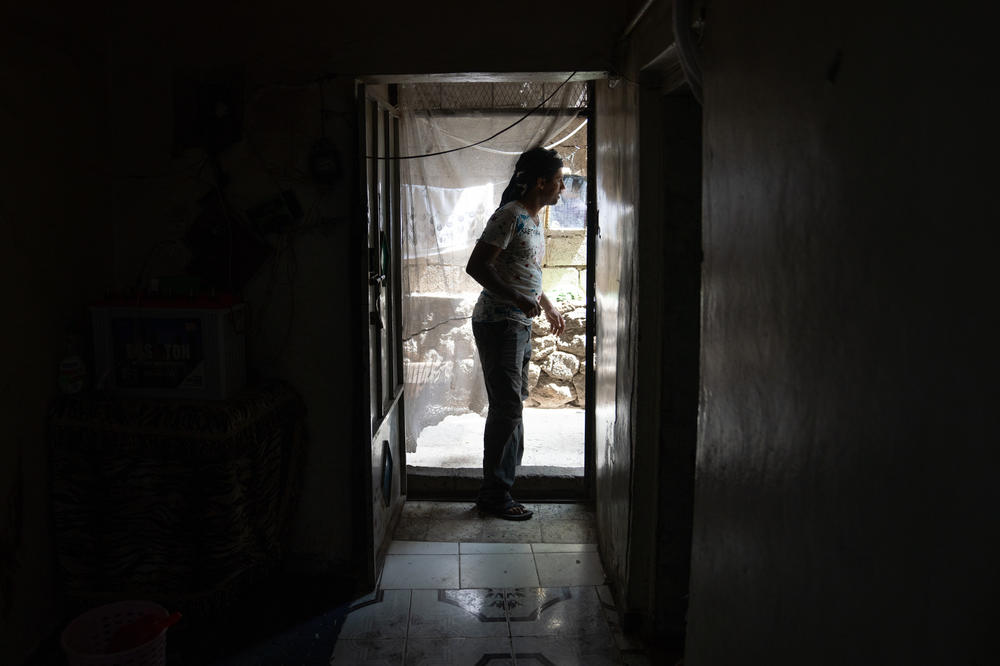 Aref Abdullah calls his daughters from the front door of his home in Al Dawah where he moved just a year ago because he couldn't afford rent at his previous home. His family is divide by the front line just him and his wife live on the Yemeni government side while both of their parents and siblings are on the Houthi side of the war and they are unable to visit each.
