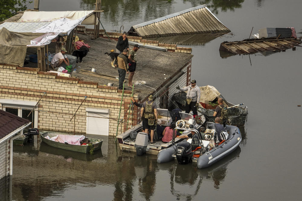 Ukrainian servicemen help residents to get down from the roof into rescue boats during an evacuation in a flooded neighborhood near Oleshky, Ukraine, on June 7.
