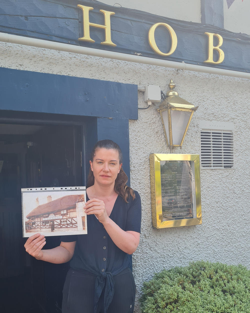 The current landlady at Ye Olde Hob Inn, Sarah Locke, shows NPR an old photo of the pub during the 1940s, when it was a favorite watering hole of Black U.S. soldiers stationed nearby during World War II.