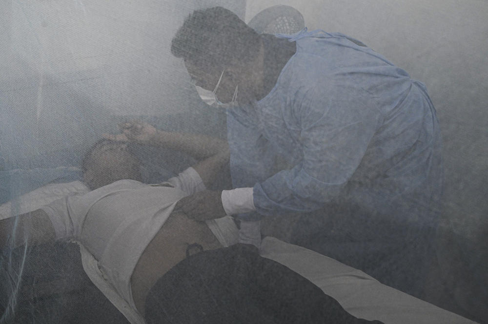 Hospitals in the city of Piura are overwhelmed during the dengue overbreak. Above: A doctor checks on a dengue fever patient under a mosquito net at the Support Hospital II. Treatment addresses symptoms.
