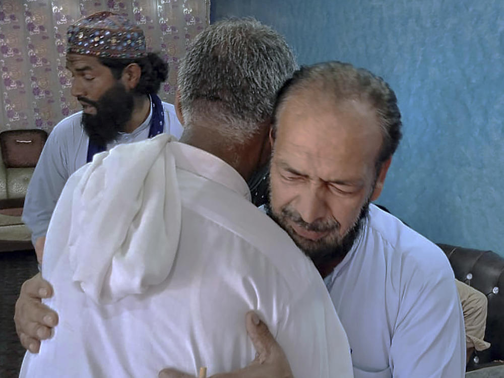 People offer their support to Raja Yousaf, right, whose son Raja Sajid is missing after a shipwreck off the Greek coast, in Bindian village in Kotli, a district of Pakistan's administrator Kashmir, Sunday, June 18, 2023.
