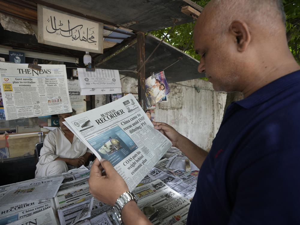A man reads a copy of a morning newspaper which reports missing Titanic submersible and onboard five people, including Pakistani nationals Shahzada Dawood and his son Suleman, at a stall, in Karachi, Pakistan, Wednesday, June 21, 2023.