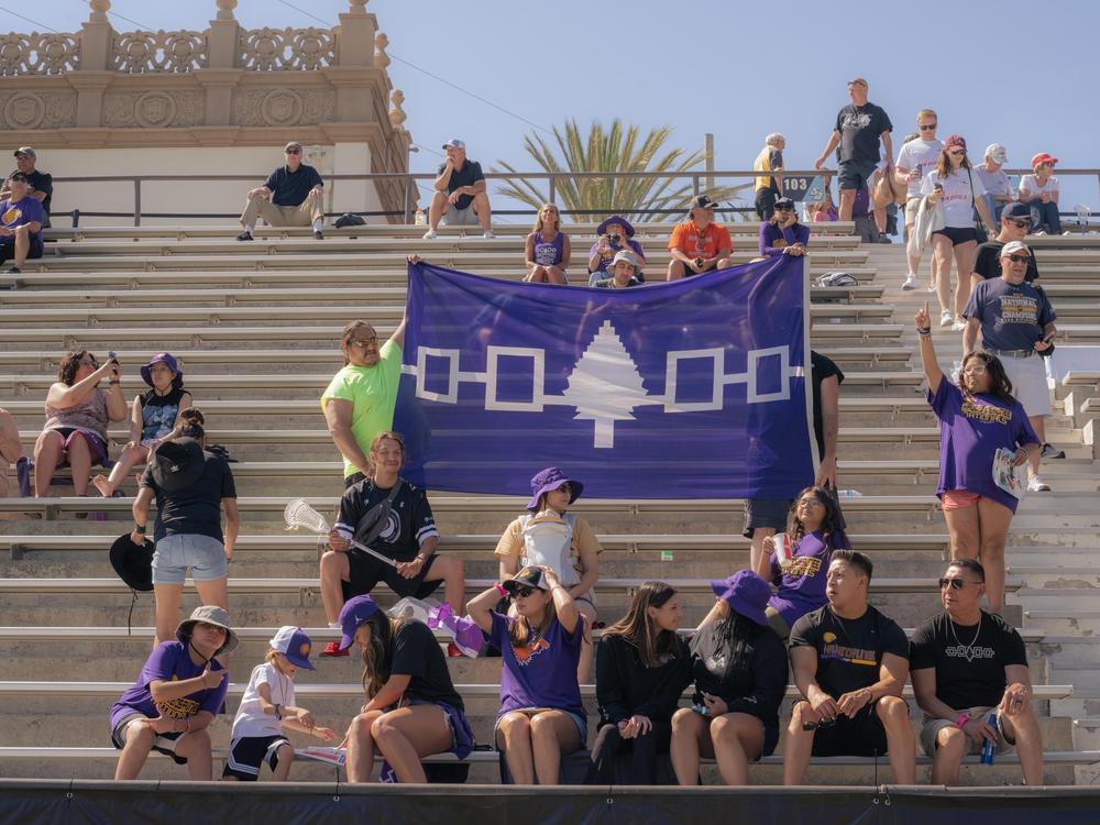 Supporters hold up a banner displaying the Haudenosaunee Confederacy Wampum as they cheer for the Haudenosaunee Nationals against England match on June 23, 2023, at Torrero Stadium in San Diego, Calif.