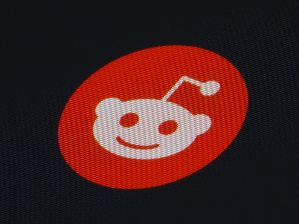 Reddit's updates will include access to moderation tools, messaging, and control settings for user approval and bans. The Reddit app icon is pictured on a smartphone.
