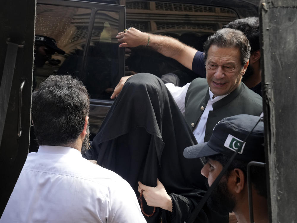 Pakistan's former Prime Minister Imran Khan with his wife Bushra Bibi, center, arrives to appear in a court in Lahore, Pakistan, Monday. Khan faces more than 100 legal cases.