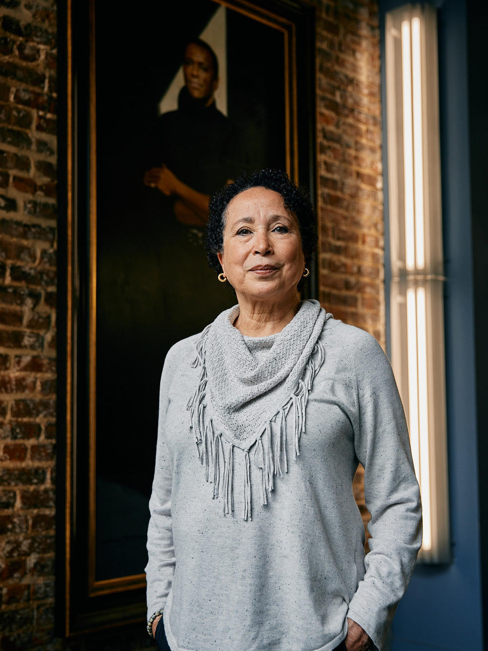 Virginia Johnson, the outgoing artistic director of Dance Theatre of Harlem, poses in front of a painted portrait of founder Arthur Mitchell on Thursday, June 22, 2023.