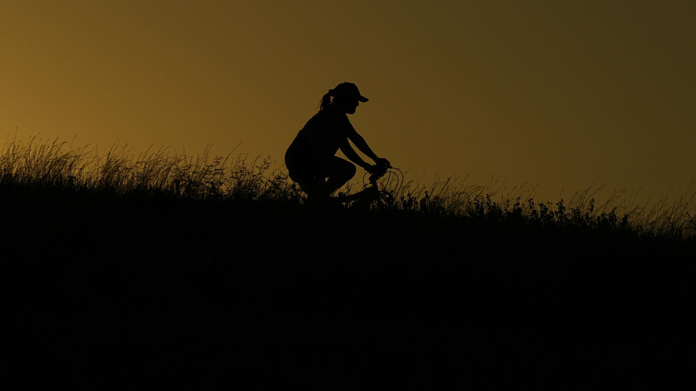 A cyclist passes through a park during an evening ride, Monday, June 26, 2023, in San Antonio.
